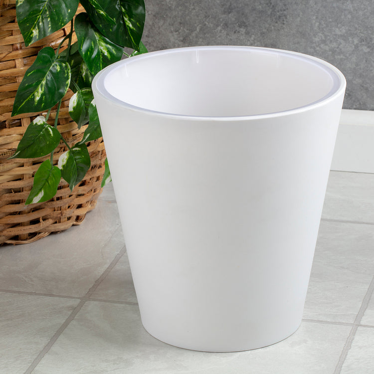 White | Madison white wastebasket with the full liner inserted inside on a tile bathroom floor.