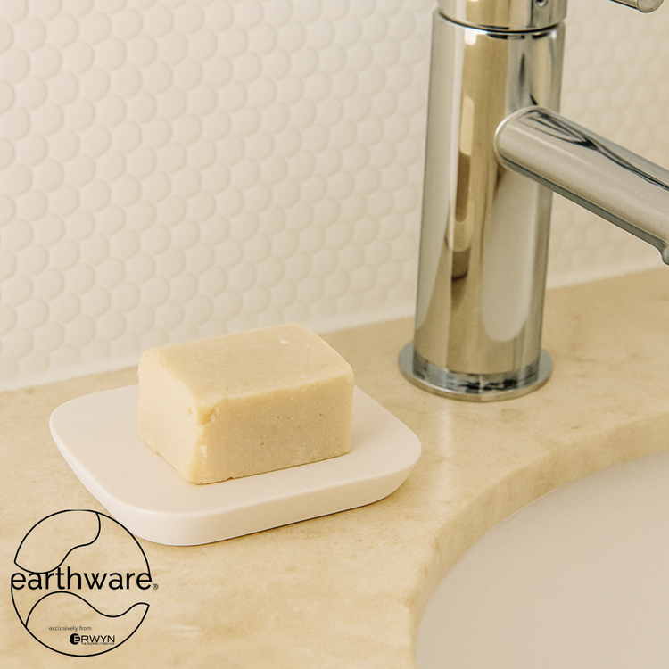 White | Soap dish on a bathroom vanity holding a bar of soap